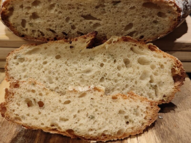 Anschnitt von hausgemachtem Sauerteigbrot mit luftiger Krume und knuspriger Kruste auf Holzbrett.