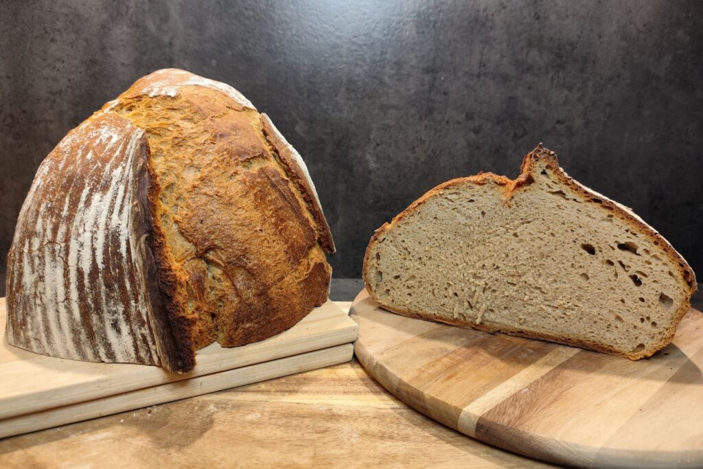 Dark Rustic Joghurt-Brot – angeschnittener XXL-Laib mit dunkler Kruste und saftiger Krume auf Holzbrett