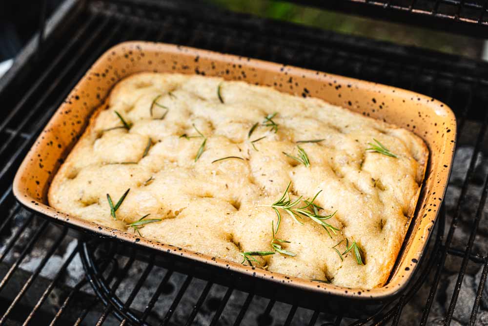 Focaccia mit Rosmarin in einer backofenfesten Form wird im Ofen gebacken.