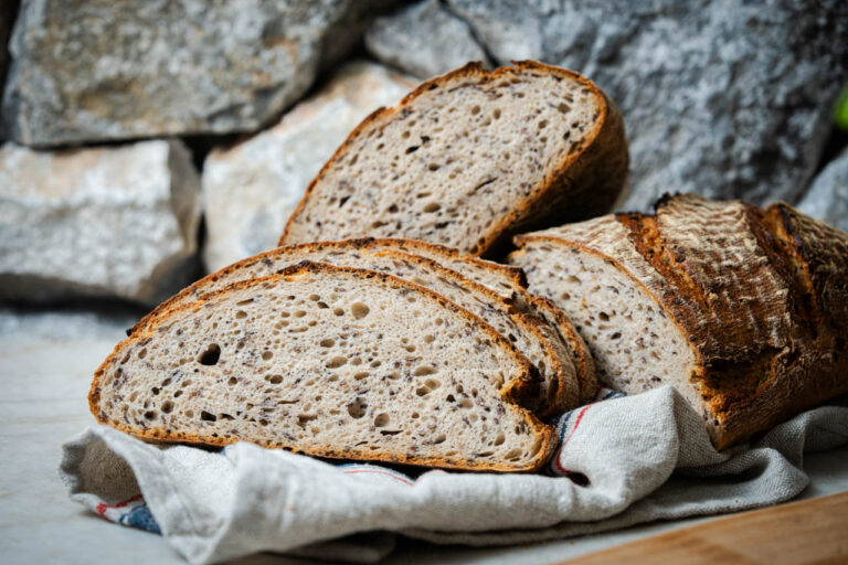 Rustikales Brot in Scheiben geschnitten, auf einem Tuch liegend, mit steiniger Hintergrundkulisse.