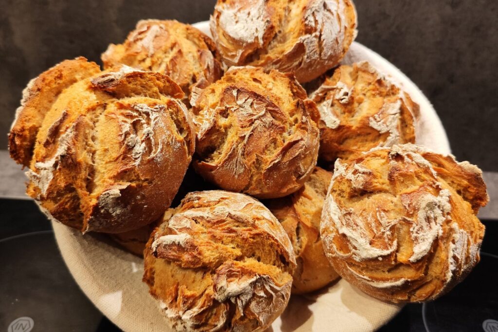 Ein Korb mit mehreren goldbraun gebackenen Brötchen mit knuspriger Kruste.